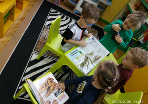 Dzieci z grupy trzeciej podczas oglądania książeczek na temat dinozaurów.